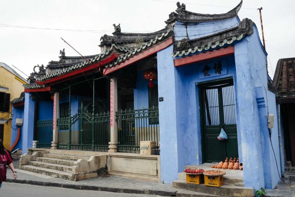 a woman walking down a street past a blue building